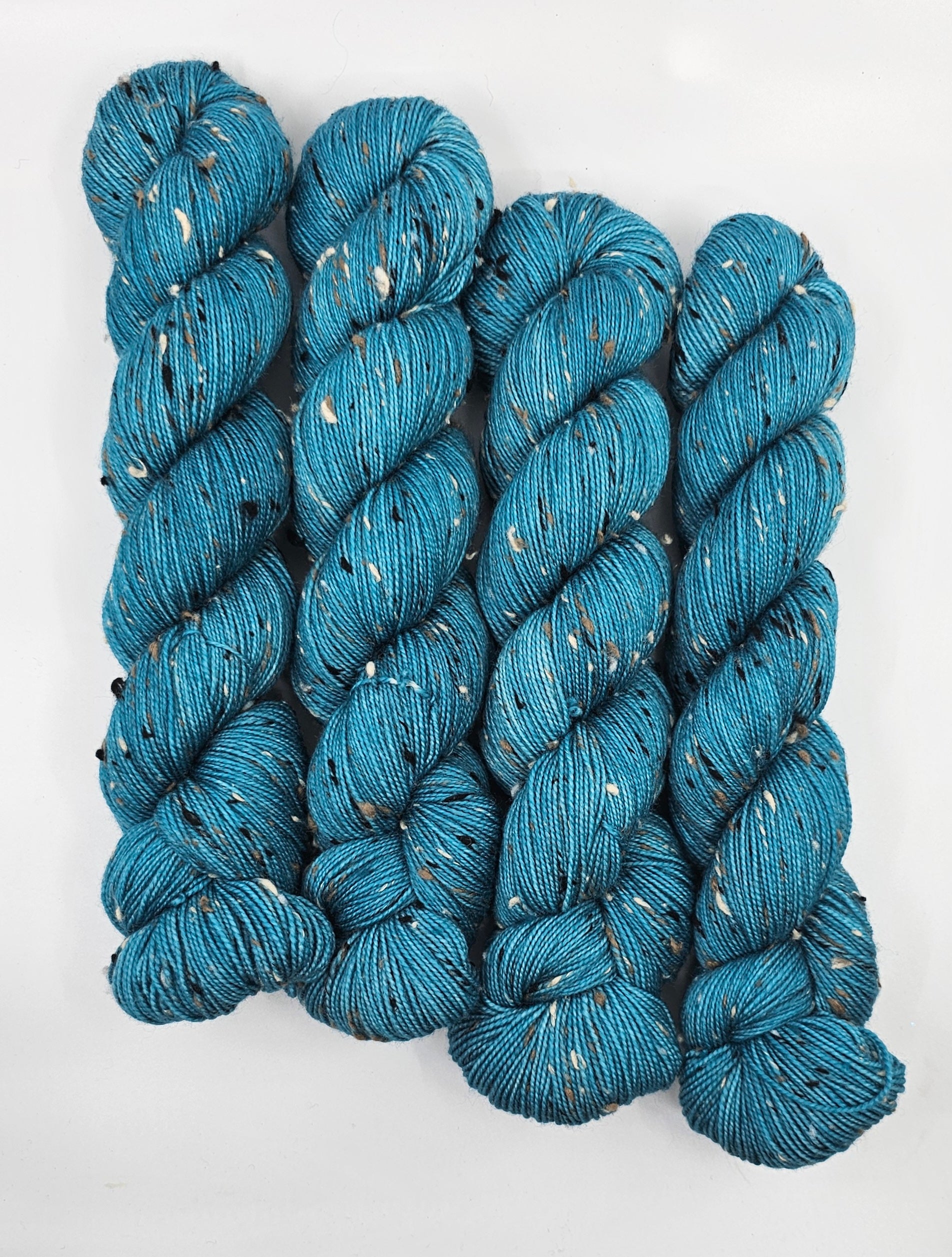 Teal skeins of yarn with donegals on a white background