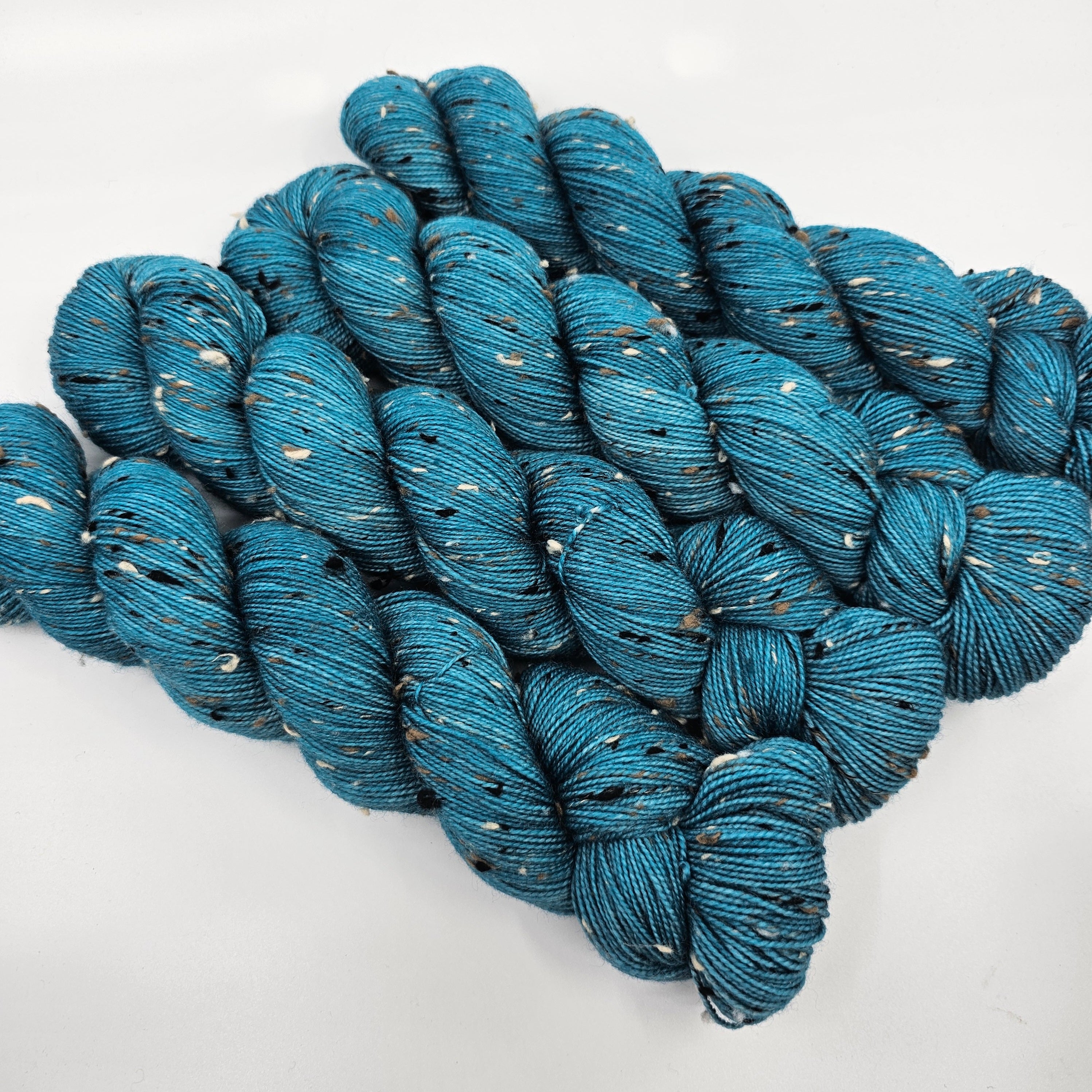 Teal skeins of yarn with donegals on a white background