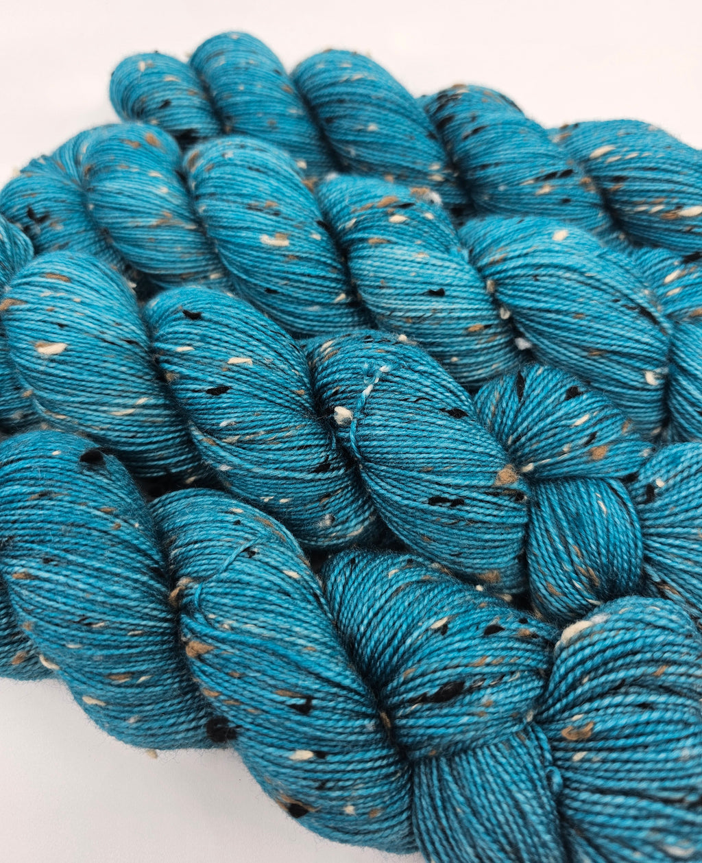 Teal skeins of yarn with donegals on a white background