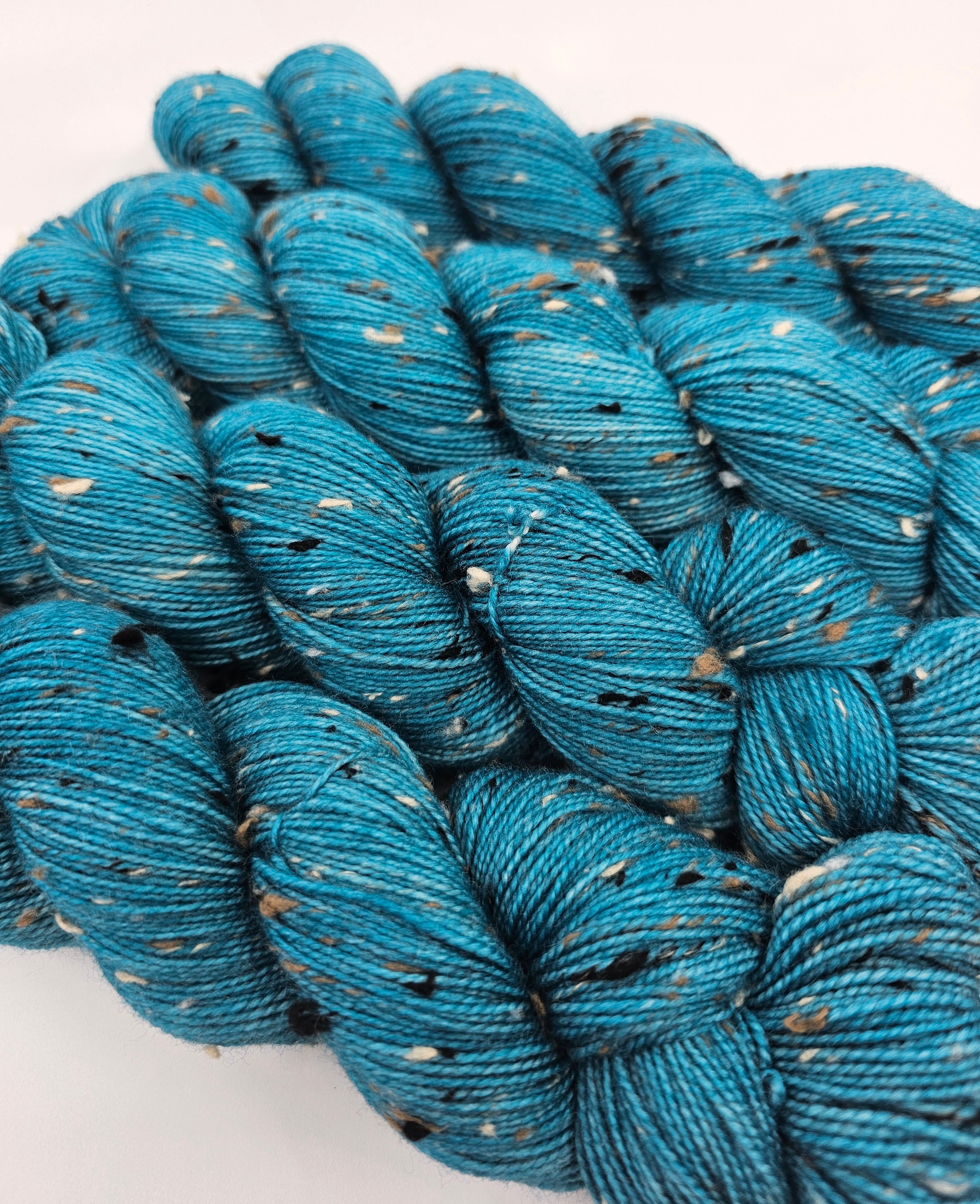 Teal skeins of yarn with donegals on a white background