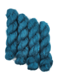 Three skeins of teal/blue mohair yarn on a white background