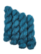 Three skeins of teal/blue mohair yarn on a white background