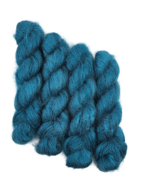 Three skeins of teal/blue mohair yarn on a white background