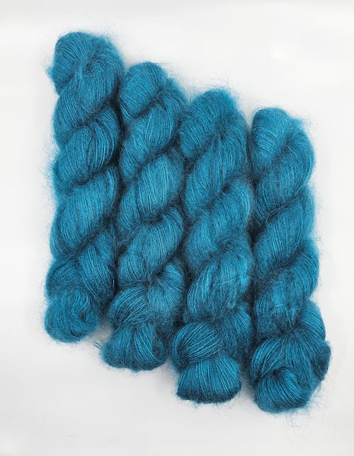 Three skeins of teal/blue mohair yarn on a white background
